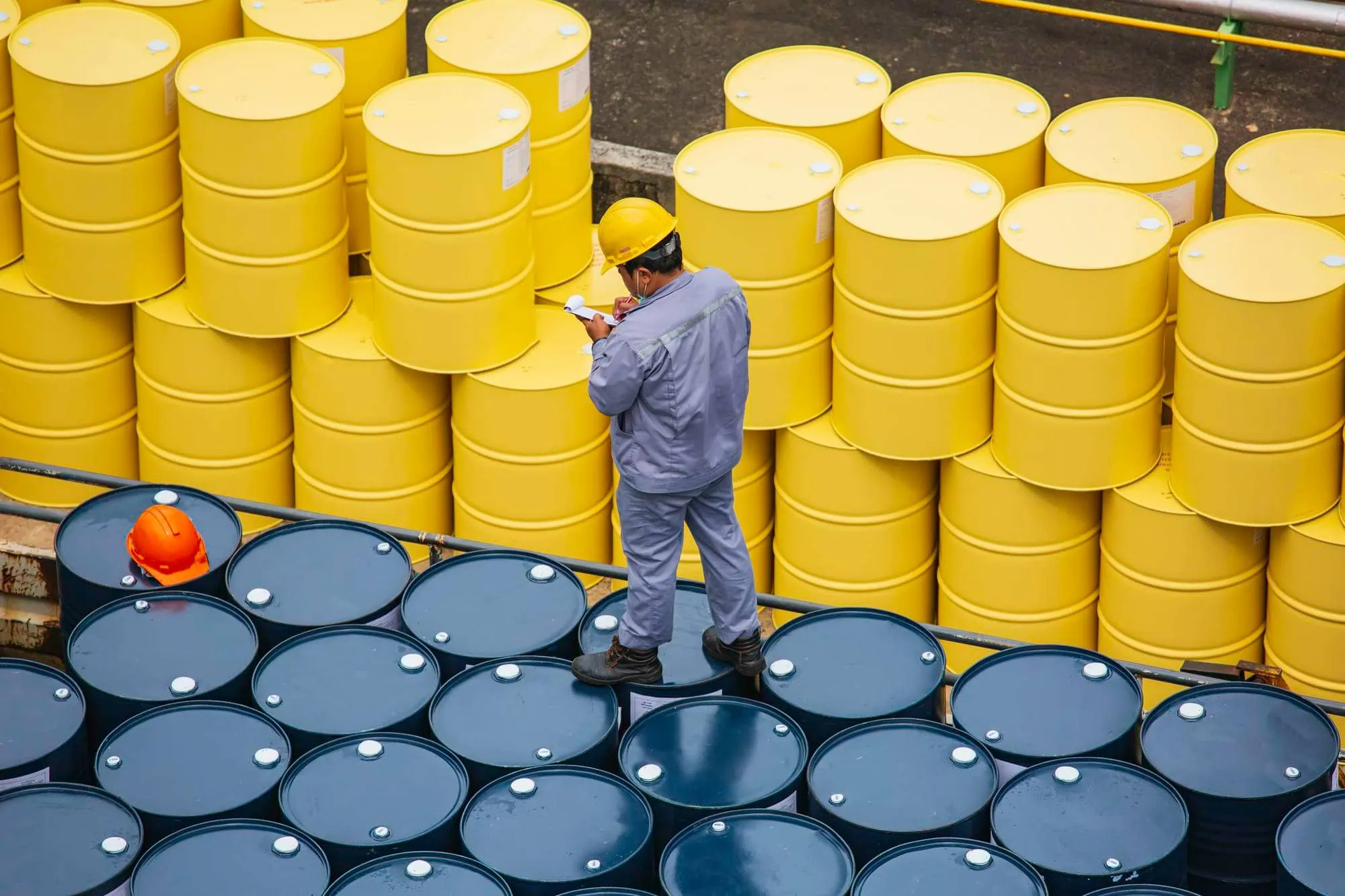 male worker inspection record drum oil stock barrels yellow vertical chemical transportation truck