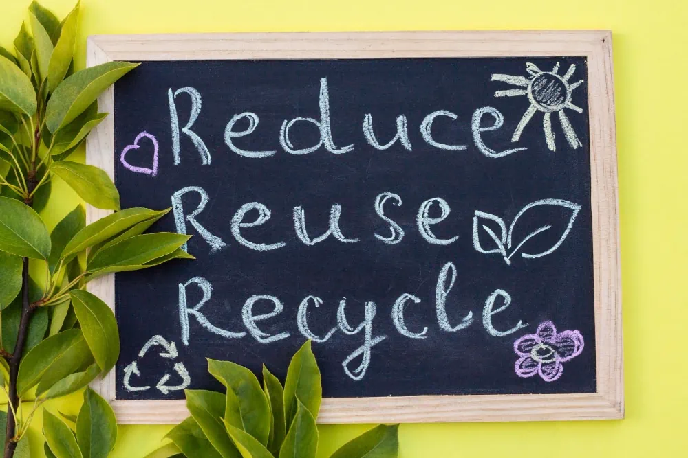 chalk board reduse reuse recycle sign yellow background with green leaves top view